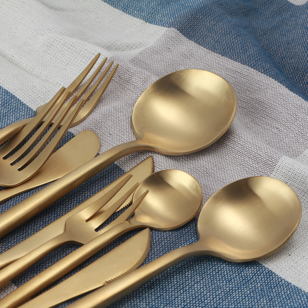 Goldenes Besteckset aus Edelstahl 18/10 im modernen Curve Design auf Stoff dekoriert