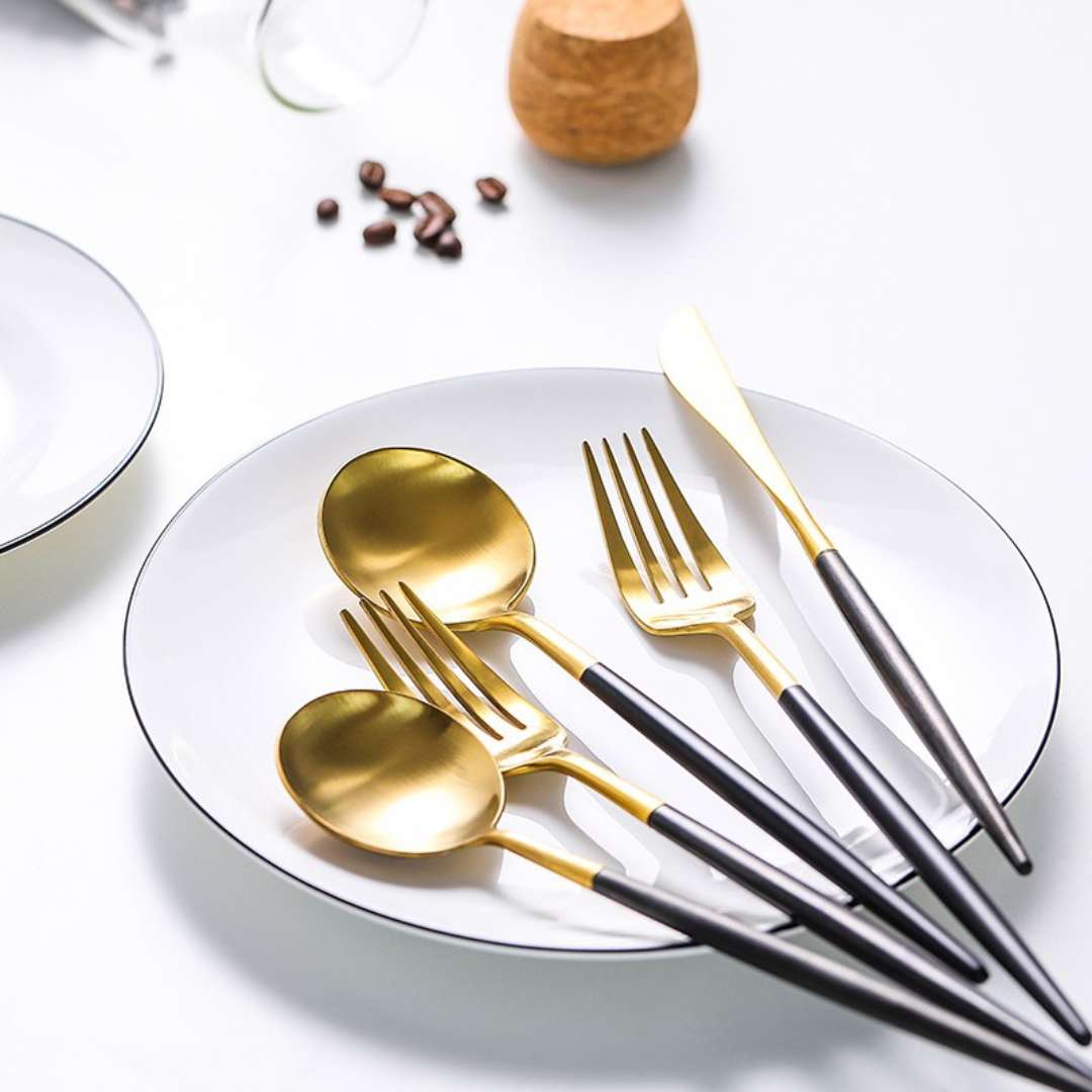Besteckset in Gold und Schwarz auf gedecktem Tisch mit Teller aus Edelstahl 18/10